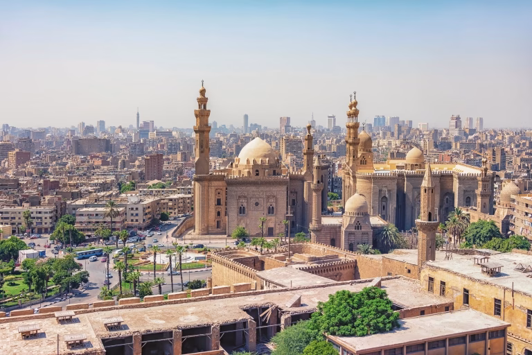 Historic Islamic mosque complex with minarets and domes overlooking Cairo cityscape