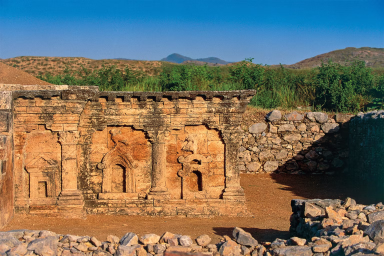 Ancient stone ruins with carved columns and arched doorways at Taxila archaeological site in Pakistan