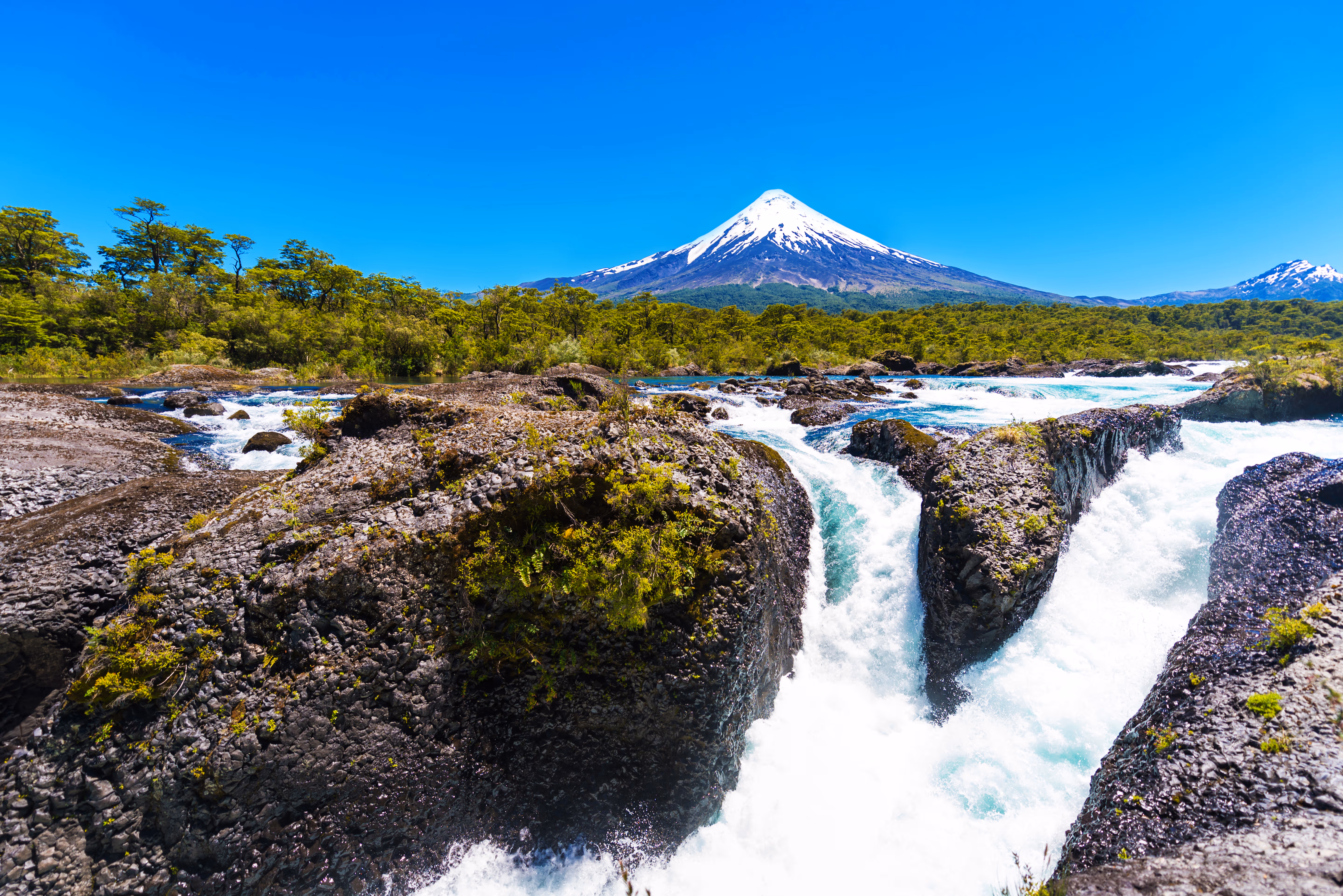 Petrohue Falls cascading over volcanic rocks with snow-capped Osorno Volcano backdrop in Chile Lake District
