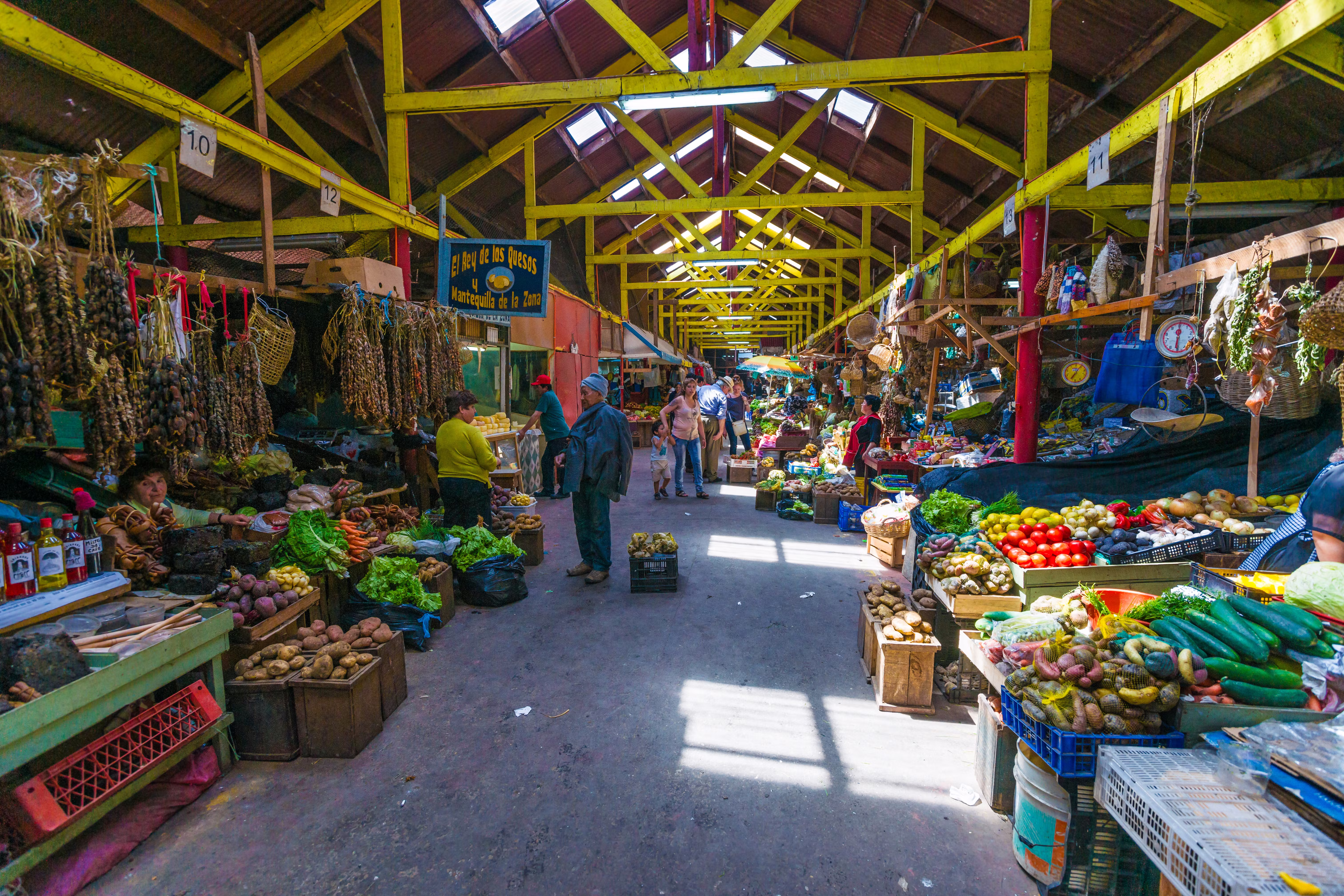 Vibrant indoor market hall in Castro, Chiloé Island with fresh local produce, vegetables, and farming goods in wooden crates and baskets