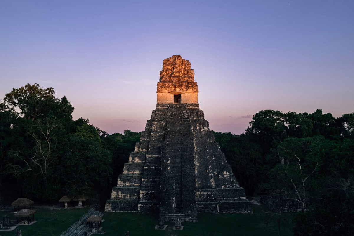 Ancient Mayan pyramid temple at sunrise in Tikal Guatemala surrounded by jungle canopy