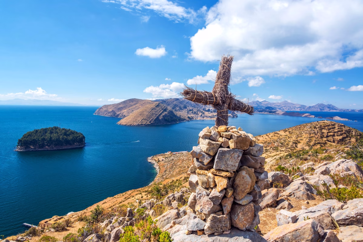Stone cairn with wooden cross overlooking Lake Titicaca islands from Bolivian highlands