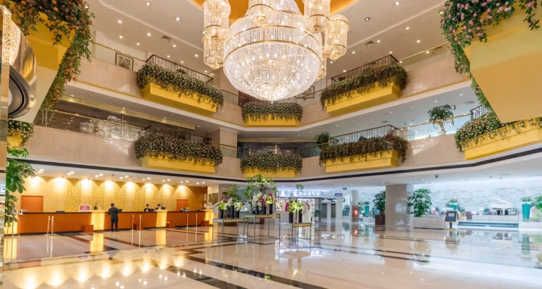 Multi-storey hotel lobby in Kunming, China, with a large crystal chandelier and tiered balconies lined with flowering plants